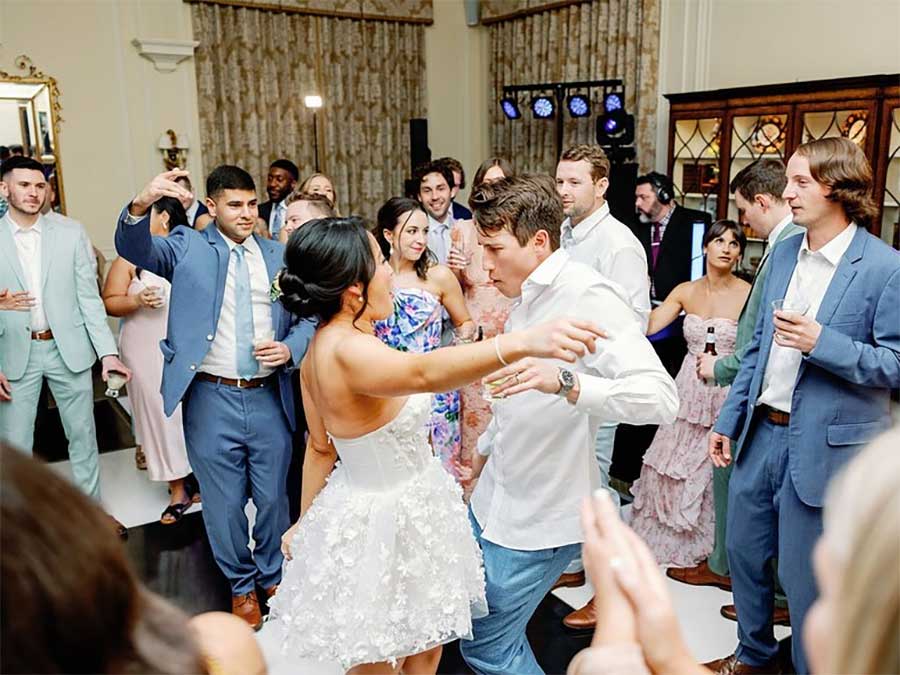 Bunn DJ Company - A group of people in formal attire dance and socialize at an indoor event or wedding reception.